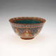 Bowl with a small base and wide, slightly flared mouth. Its turquoise interior’s rim features red and golden patterns. Its outside features sitting figurines against red, golden, and blue patterning.