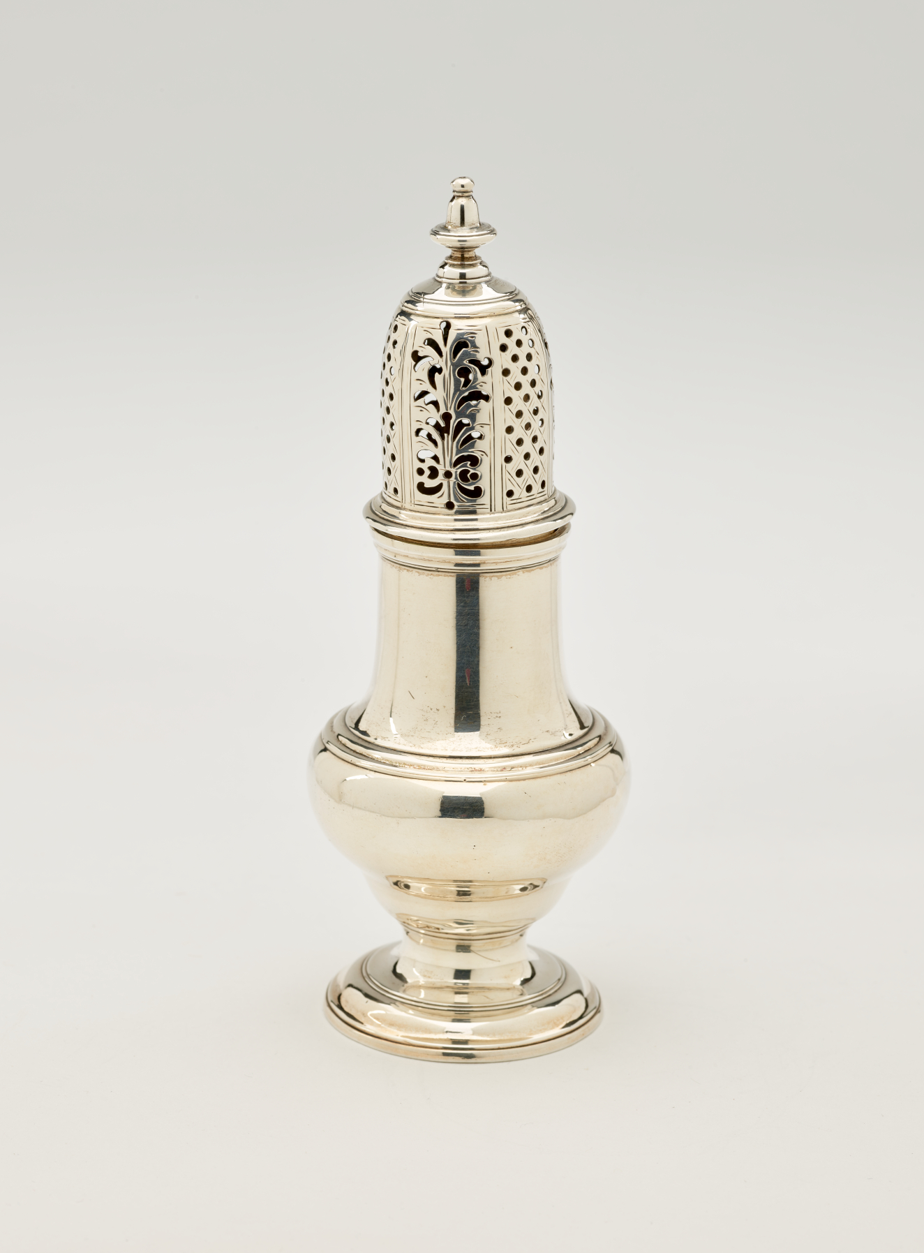  A silver vessel with a foot, rounded body that goes to a cylindrical top half, and the lid is perforated with small holes and floral cutouts.