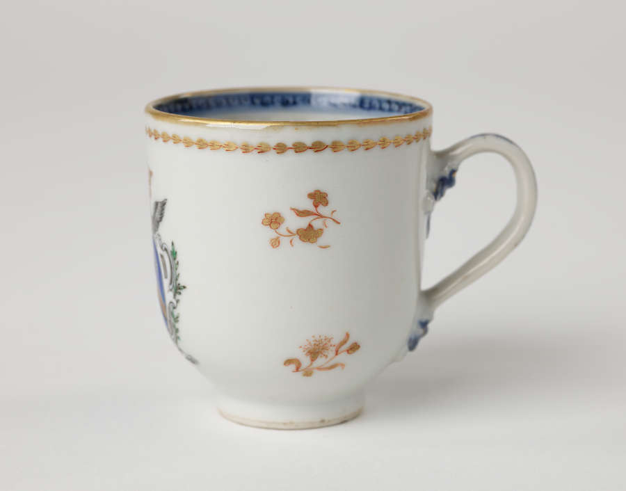 A cup with blue and gilded decorations along the outside and inside of the rim, body, and handle.