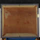 The back of a painting with a reddish ground, secured into a metal frame with clips and an identification tag on the right.