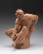Realistically carved terracotta sculpture depicting a muscular bearded man facing left, sitting and leaning over a vessel he’s holding between his legs while keeping his body in tension.