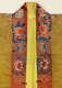 The collar of an embroidered robe with symmetrical floral motifs in red, blue, and white, along a vertical border. A central yellow strip contrasts with richly decorated edges. 