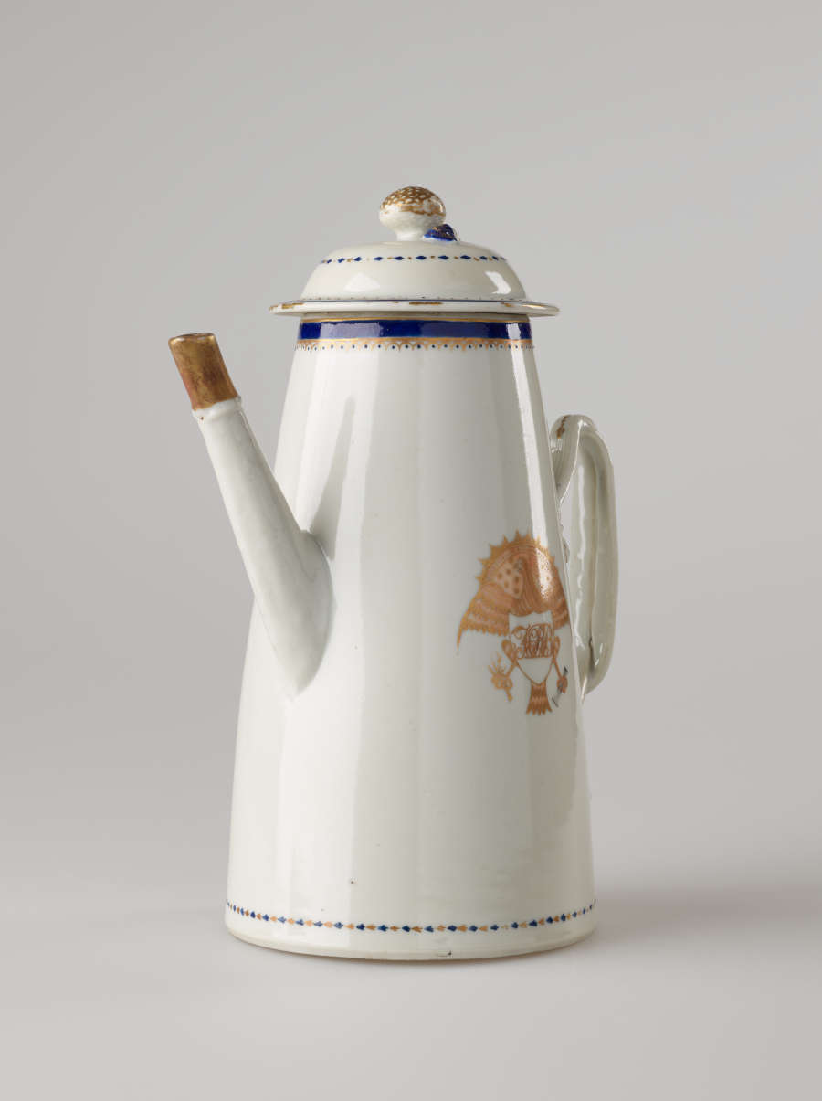 A white, blue and gilded teapot with a long straight spout, a handle, and lid. The central decoration depicts a heraldry bird with a shield and objects in its talons.