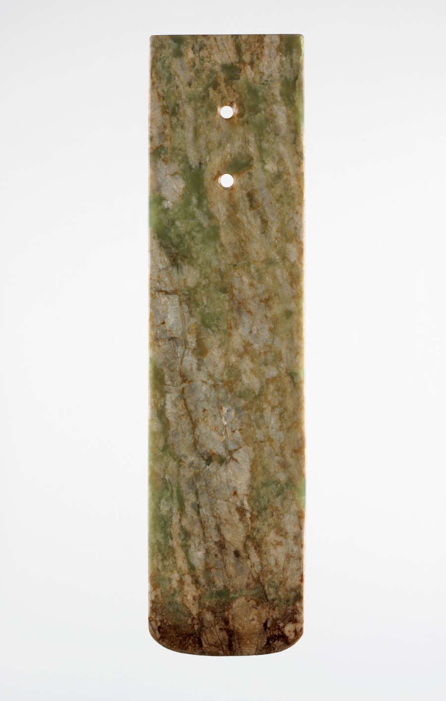 A long, rectangular stone blade with two holes punched below its top edge. The bottom edge is slightly rounded. The blade is a smooth, marbled green and brown texture.
