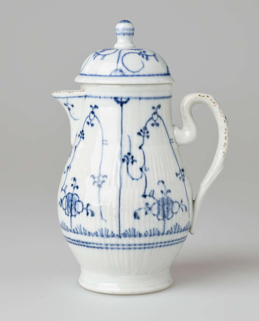 A white chocolate pot with delicate blue decorations with ribbed body, spout, handle, and foot.