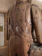 Close up of an aged wooden statue with visible cracks and metal reinforcements.