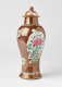 A brown and white covered vase with pink, green, blue, and yellow floral decorations.