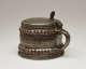 A brown and tan mug with a silver, scalloped rim.