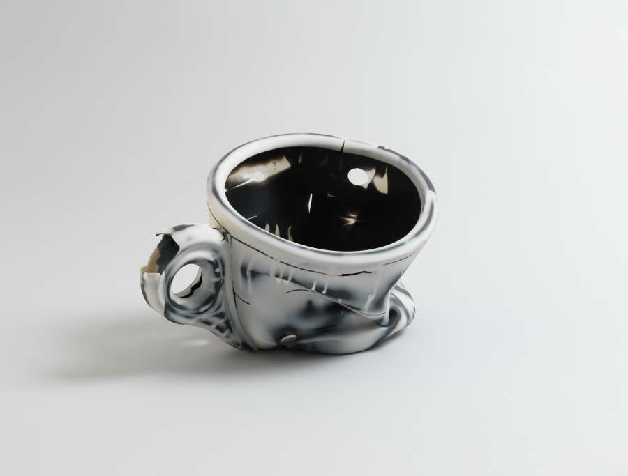 Warped ceramic teacup marbled with a glossy black-and-white glaze, appearing partially melted with folds and distortions collecting on the bottom half of the vessel, the surface resembling an ink painting.