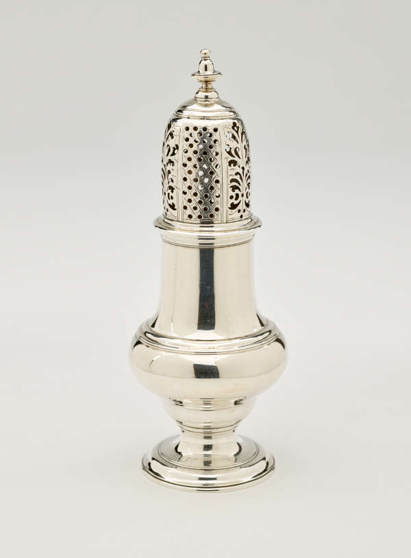 A silver vessel with a foot, rounded body that goes to a cylindrical top half, and the lid is perforated with small holes and floral cutouts.