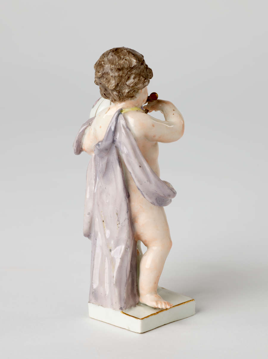 A sculptural putto figure holding a globe banded with gold. The putto has brown hair, red lips, and a light purple fabric draped across their body.