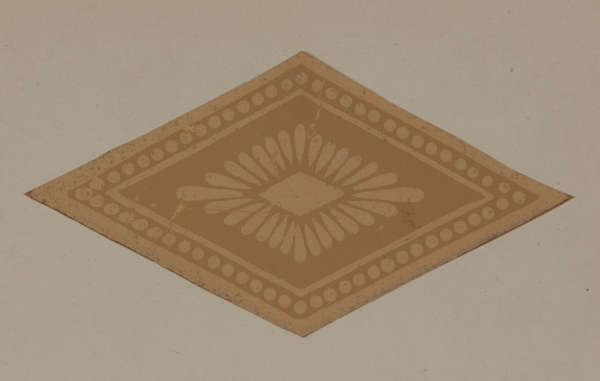 A brown diamond shaped emblem with petals radiating from the center surrounded by a decorative dotted border with solid bands.