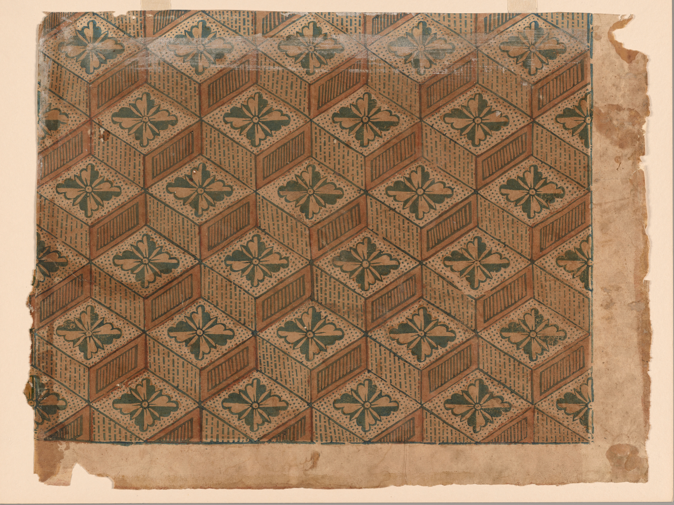 Aged, light brown wallpaper of repeating cubes stacked on top of each other each with a flower design on top made out of alternating green and white petals. 