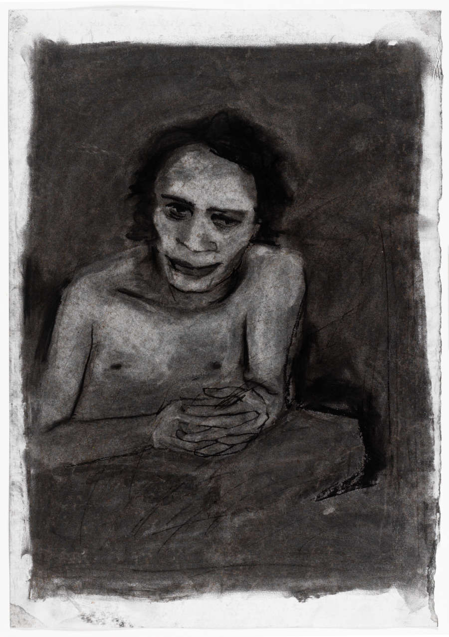 Subtractive charcoal drawing of an imagined male figure. Leaning forward, he has his fingers interlaced and wears an ambiguous expression on his face.