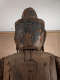 The rear view of the head of a wooden statue, with cracks and visible repairs.