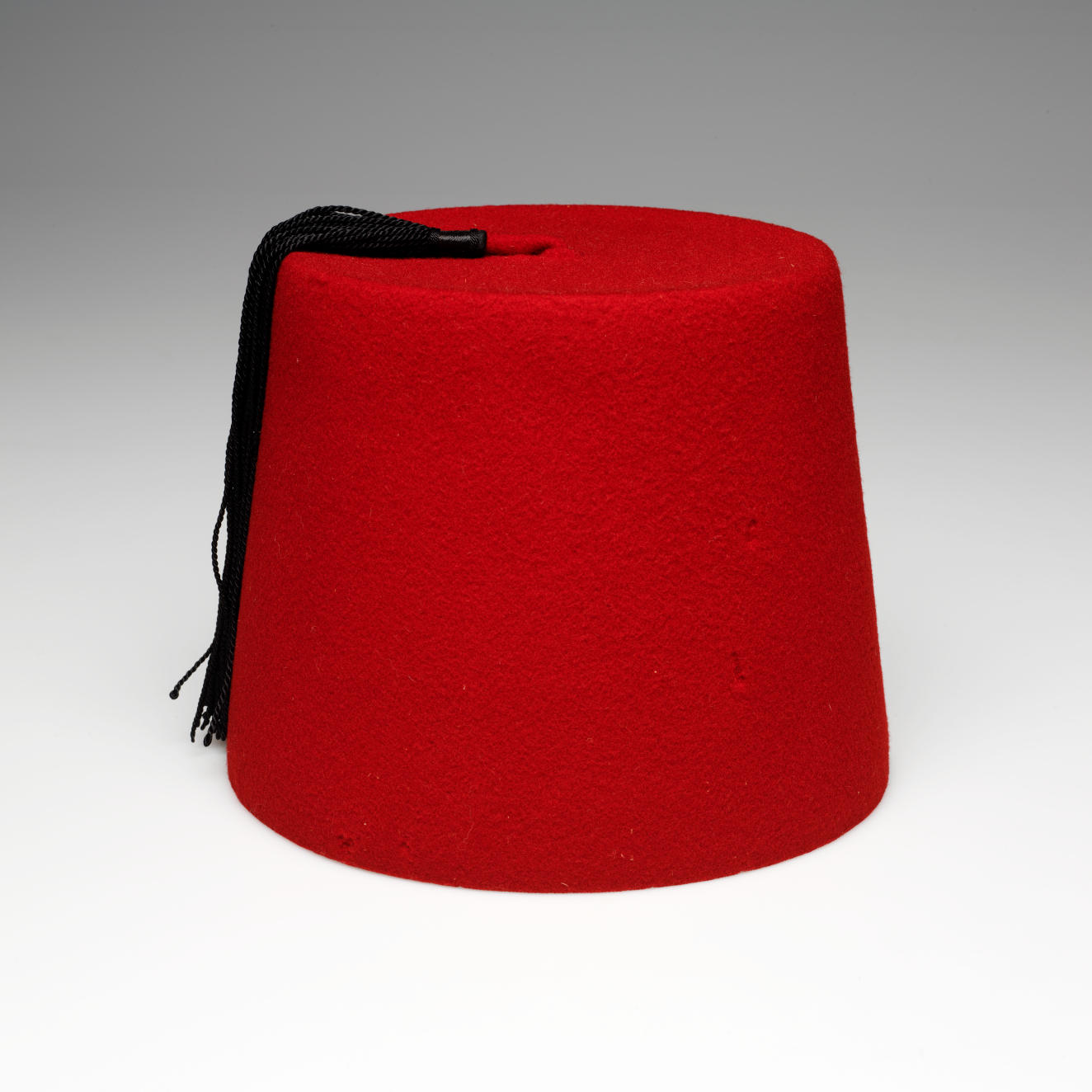 A bright red cylindrical hat with a black tassel hanging from top to the left.