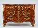 An antique reddish-brown wooden dresser with three drawers and intricate swirling gold detailing. The top surface is composed of red marble with white veining. 