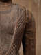 The shoulder of a wooden Buddha statue showing the intricately carved robe draped over the torso, with deep cracks and a rough, aged surface.