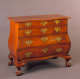 A warm brown wooden dresser with flowing lines, ornate handles, and decorative clawed feet.