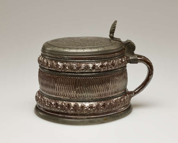 A brown and tan mug with a silver, scalloped rim.