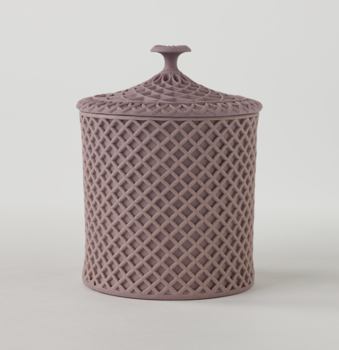 A purple covered cup with raised woven texture. The handle is sculptural and swirled.