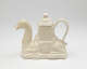 A cream colored teapot in the shape of a camel with a hexagonal lid.
