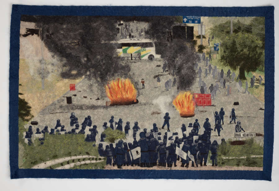 Textile image of a protest. Two fires, dark smoke clouds, and a dispersed group of people are center-right in an otherwise desolate plaza. Police in riot gear are positioned below.