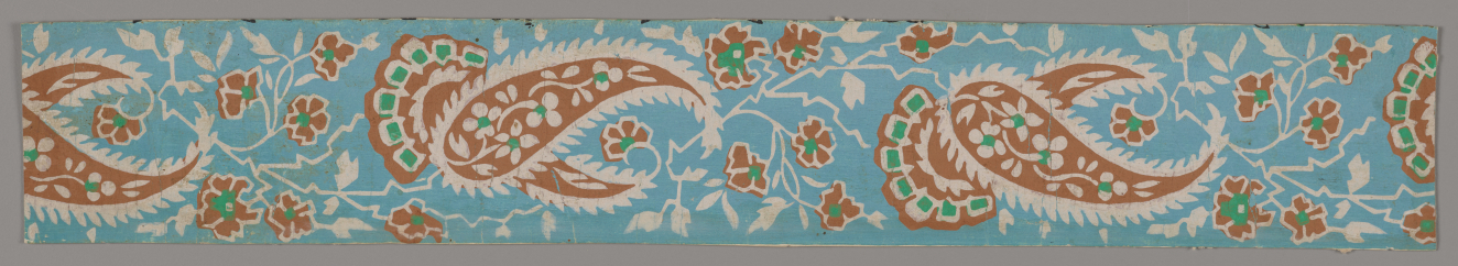 Thin strip with repeating orange teardrop and floral ornamentation with white and green accents, interspersed with white vine and leaf linework against a light blue background.