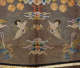 A symmetrical, embroidered design depicting two cranes, multicolored clouds, gold medallions, and phoenixes, set against a golden mesh. 