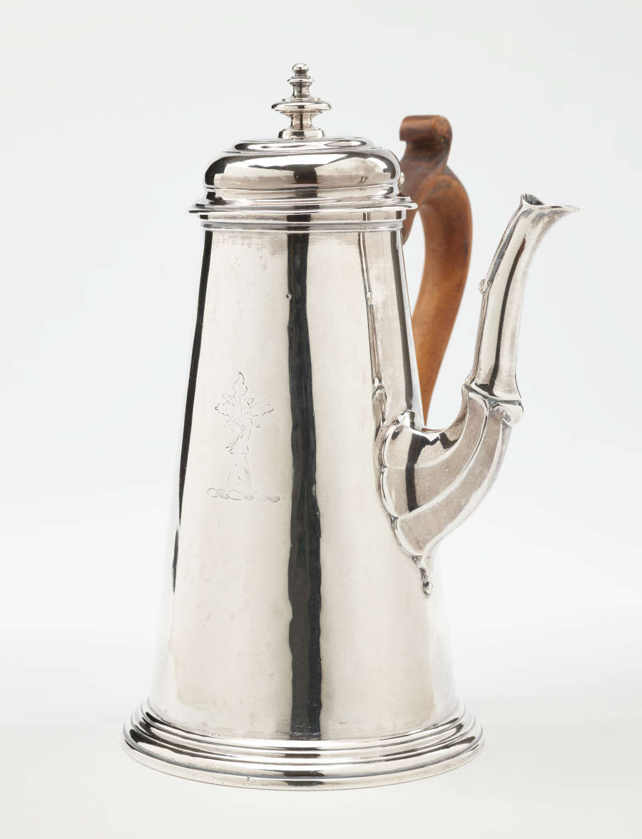 A silver chocolate pot with a spout, hinged lid, and fruitwood handle that is 90 degrees from the spout.
