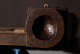 Close up of a circular end of a wooden beam with a deep, smooth, concave indentation, with evidence of age and wear. 