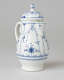 A white chocolate pot with delicate blue decorations with ribbed body, spout, handle, and foot.