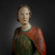 The face of a softly illuminated wooden statue, featuring delicate facial features and a serene expression.