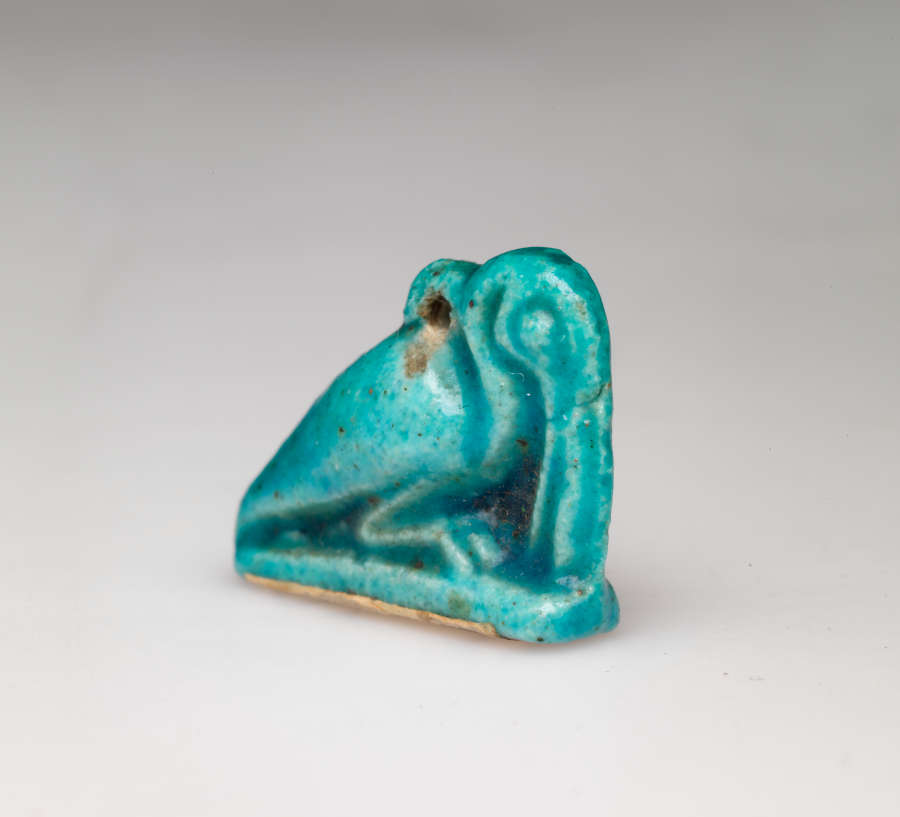 Turquoise amulet at an angle, of a crouching pelican-like bird with a long beak pointed downwards, head tucked into its neck, where there is a small loop.