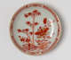  A cream colored plate with red and gold floral, structural, and abstract decorations.