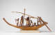 A painted wooden model of a boat with human figures rowing and working with a mast and oars.