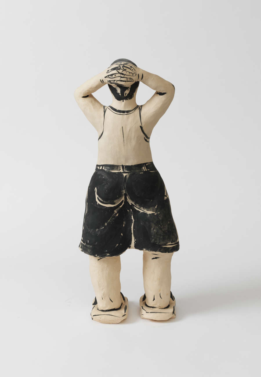 A stylized figure of a boy wearing black shorts and sandals from behind, posed with arms raised and hands clasped behind his head.