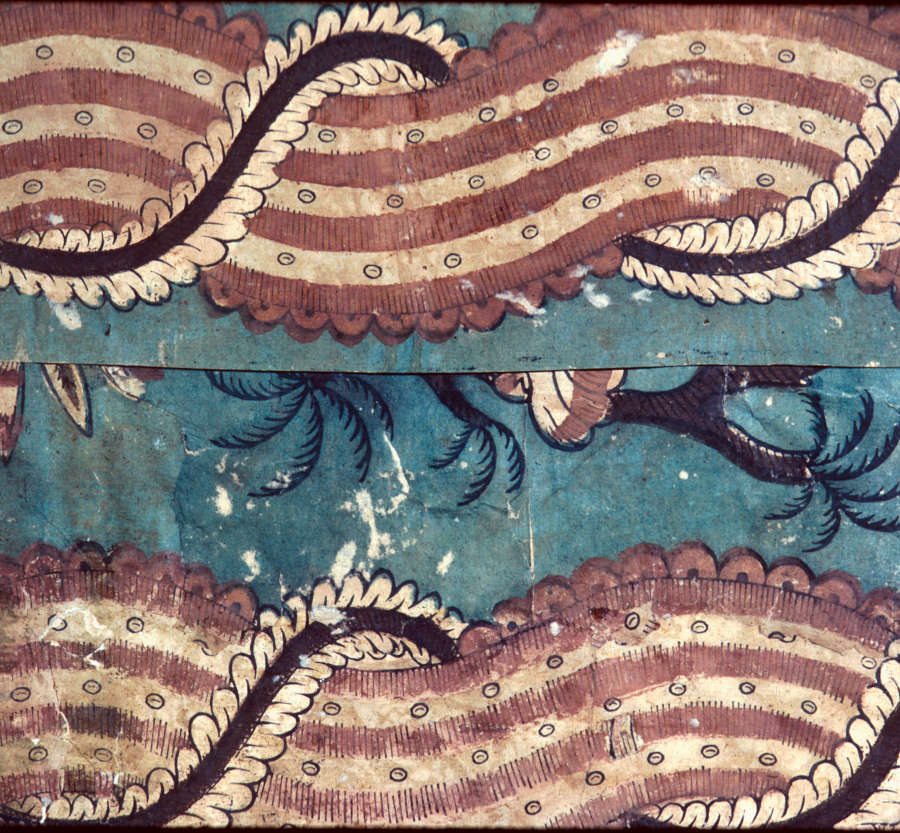 Segment of aged wallpaper featuring undulating red and white striped motifs bordered by intricate curved details and an ornamental spiral wrapping around the motif; set against a faded blue backdrop.
