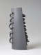 Side view of a cylindrical gray ceramic sculpture featuring a row of protruding loops threaded along its periphery.. The opposing side is flat with similar forms organized in a row.