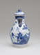 A white and blue chocolate pot with a spout, handle, and lid, the edges of the lid and spout are gilded. The decorations mainly depict floral, architectural, and landscape elements.