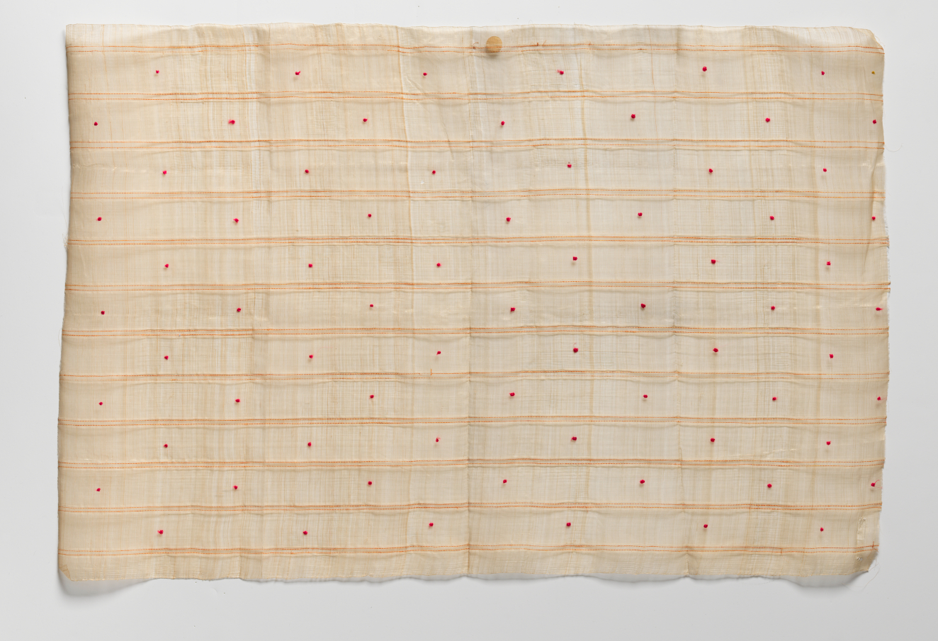 Rectangle of softly wrinkled beige fabric on a light background with uneven edges. The surface features textured horizontal stripes with evenly spaced small red dots in between them.