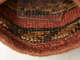 Detail of the bag’s interior showing the rough wooly texture. Red rows alternate orange, black, and cream woven rows.  A clear rectangle stands in the center keeping the bag open.