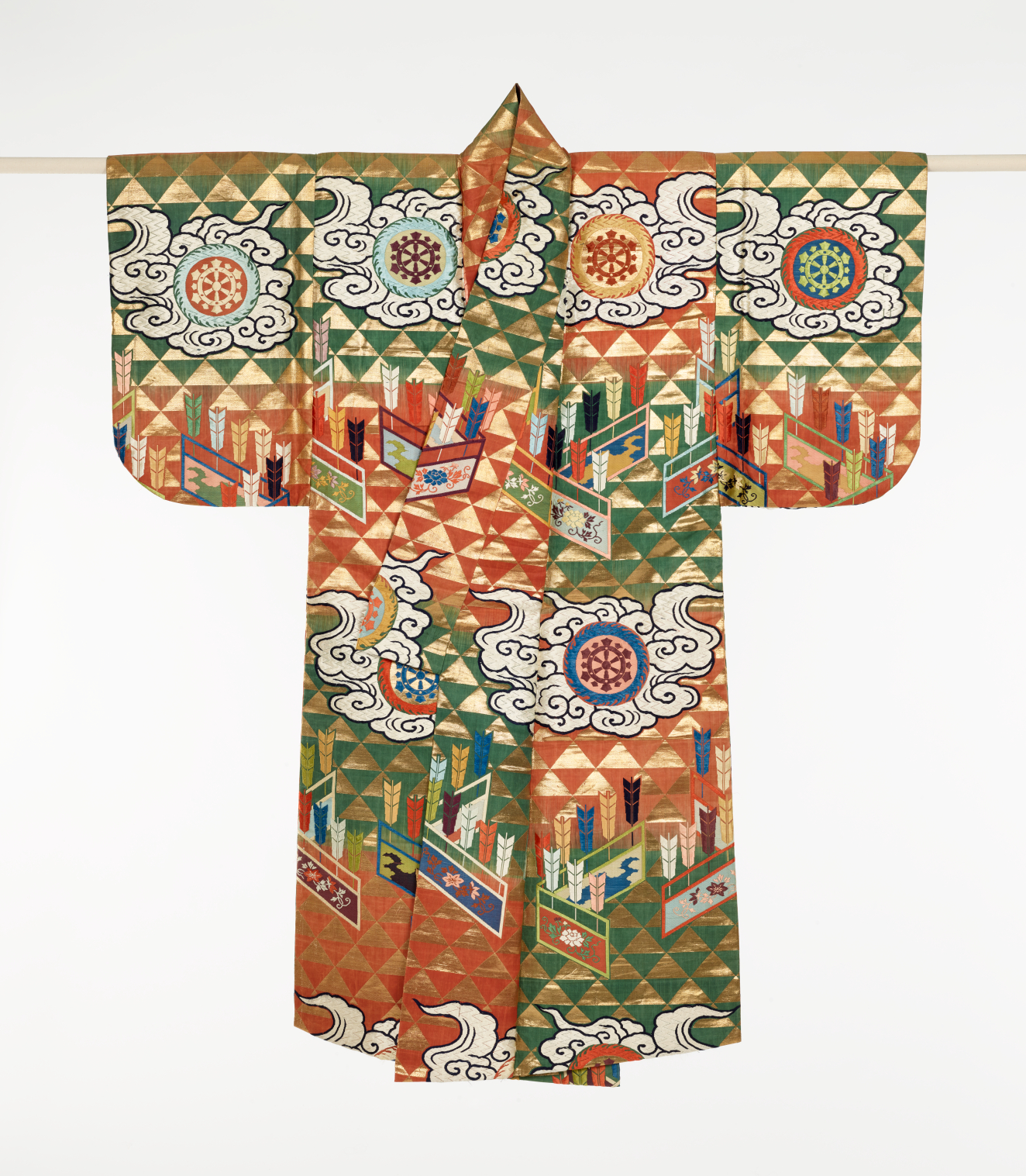 Elaborate garment patterned with alternating gold triangles, layered over orange and green panels. Each panel is decorated with colorful arrows, swirling clouds surrounding elaborate medallions, and embroidered walls.