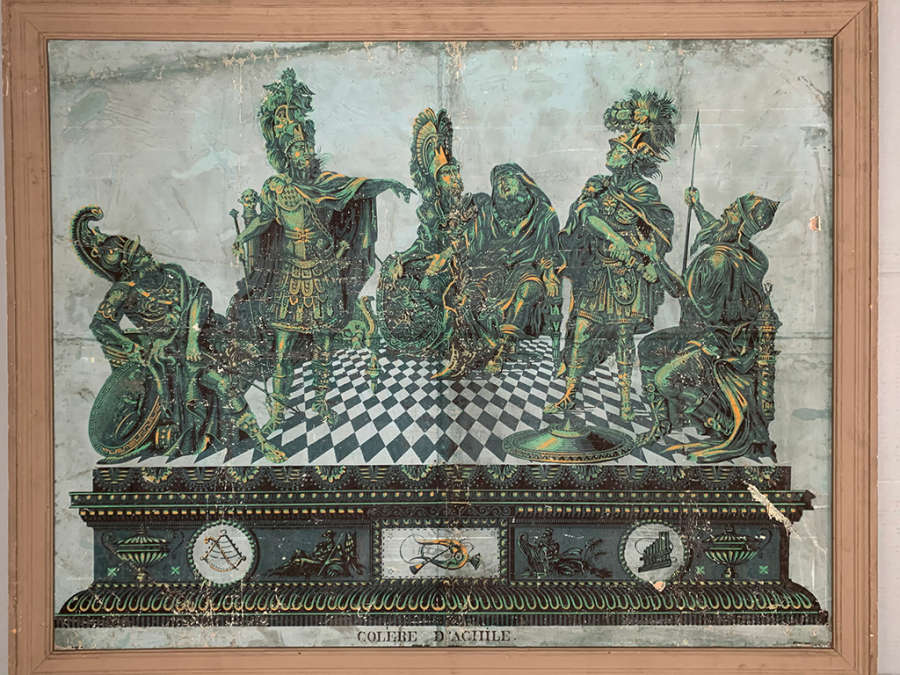 Framed, aged print of five armored, emerald green figures on a raised checkered floor. Several symbols line the base of the checkered floor and text below reads “ “colere d’achile.” 