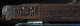 Close up of a carved wooden beam with interwoven geometric patterns and a calligraphic inscription on the left end. 