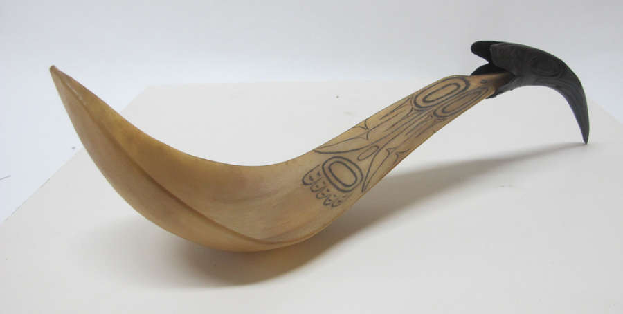  Ladle’s side view, showing that it forms a wave-like shape. The tip of the spoon’s bowl is pointing upwards, with the neck sloping upwards, while the thin black handle points downwards. 

