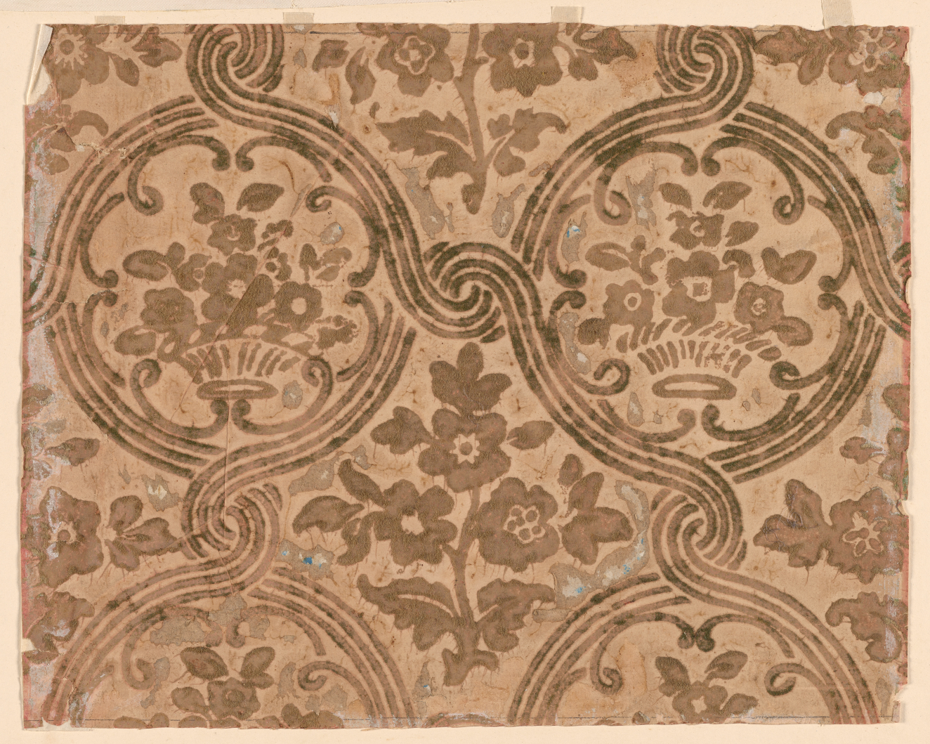 Segment of vintage wallpaper depicting a rustic pattern of brown florals and intricate swirl motifs on a richly tan-toned, textured background.