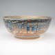 A ceramic bowl ornamented with a vibrant, bustling cityscape including buildings, figures, and boats in vivid colors and fine details. 