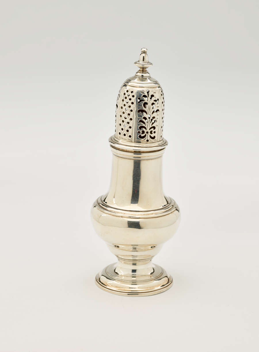  A silver vessel with a foot, rounded body that goes to a cylindrical top half, and the lid is perforated with small holes and floral cutouts.