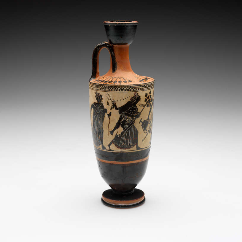 Tall vase with a slender neck. Its tan-orange surface is decorated with black illustrations of robed figures walking and carrying branch-like objects and jars, as well as stripe patterns. 